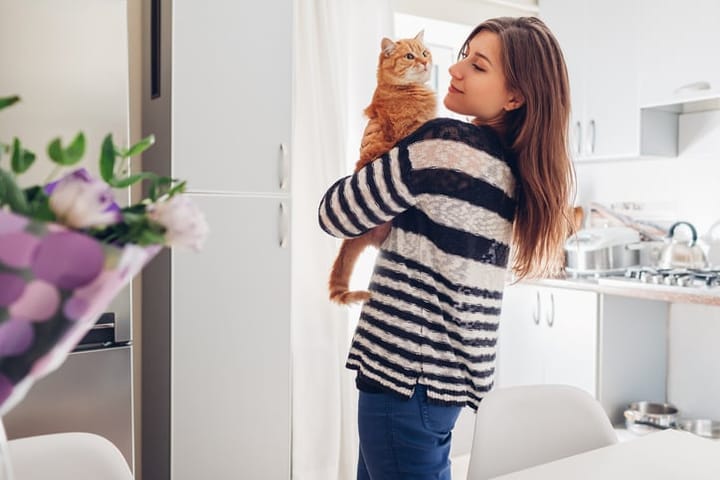 woman standing inside her home with a cat