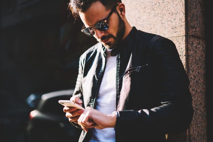 guy texting in sunglasses outdoors