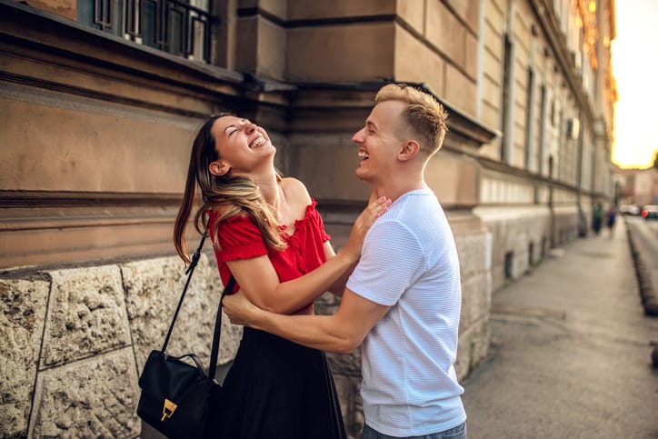 couple laughing on sidewalk at sunset