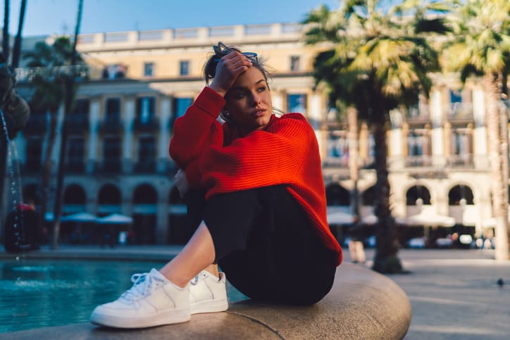 Unhappy woman sitting at the fountain and staring away