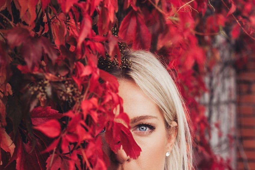 woman hiding behind red bush