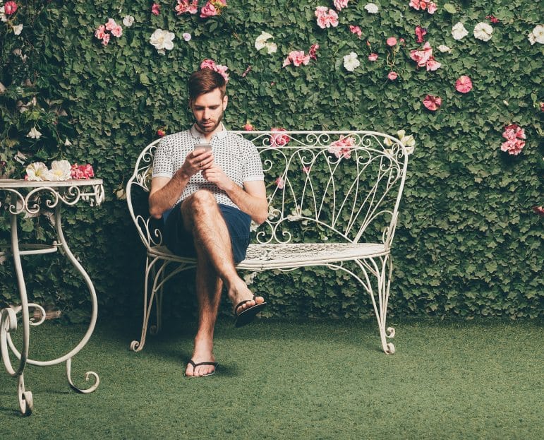 Man in flip flops on garden furniture.