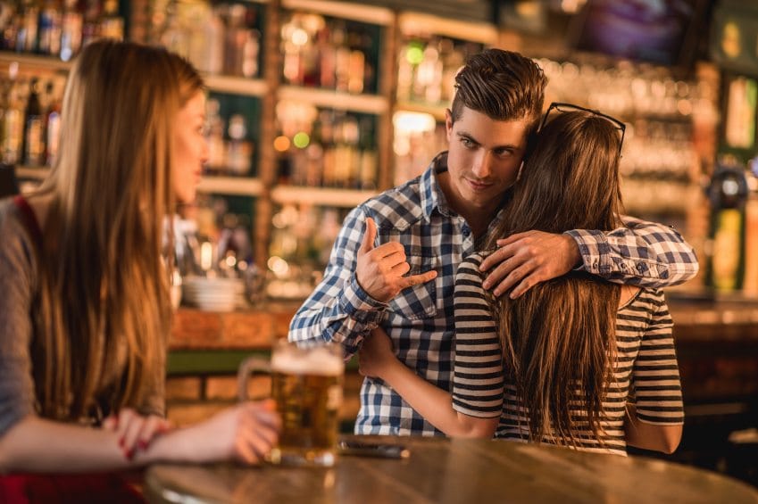 Unfaithful man making call gesture at bar