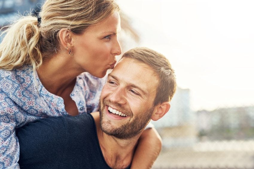 Woman kissing smiling boyfriend's head