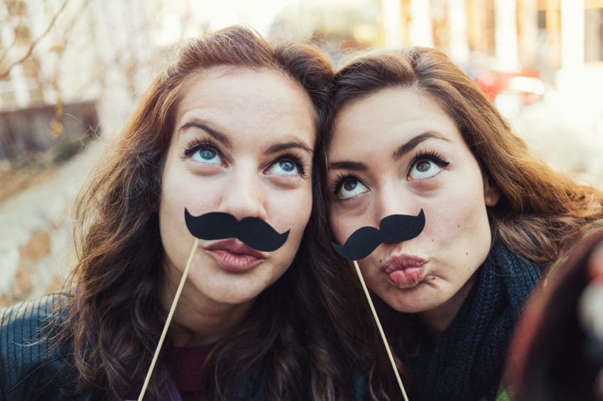 Best friends posing with fake mustaches.