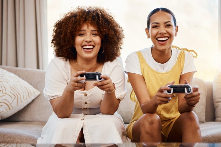 two friends playing games on couch