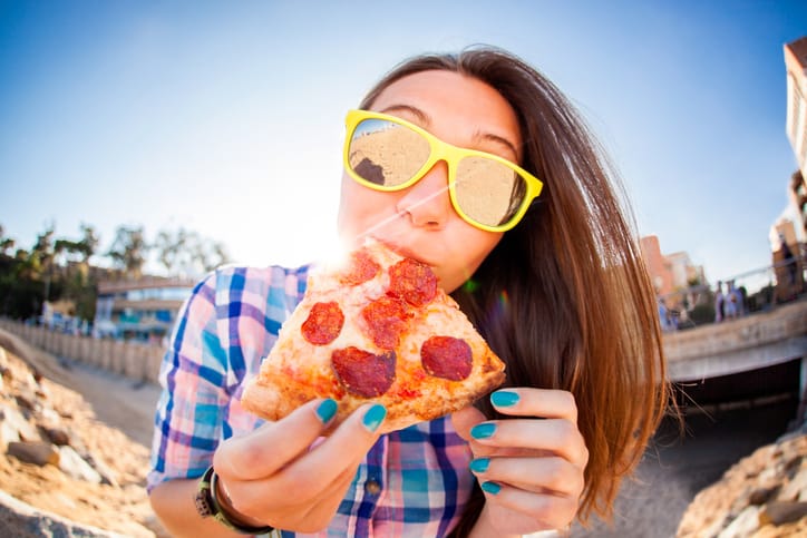 Close-up Of A Happy Young Woman Wearing Sunglasses Eating Pizza