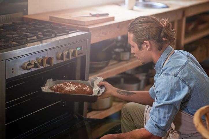 Man putting a bread in the oven.