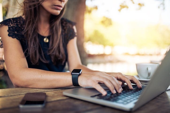 Young woman wearing smartwatch using her laptop.