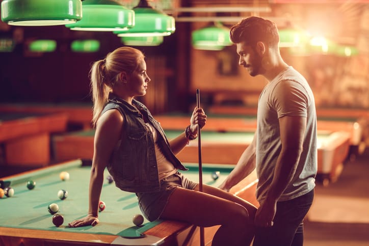 Young couple communicating in a pool hall.