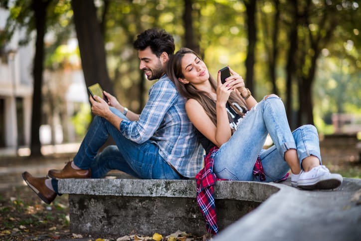 Young couple in the park sitting back to back