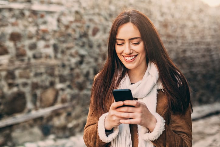 A young woman texting on the phone outdoors.