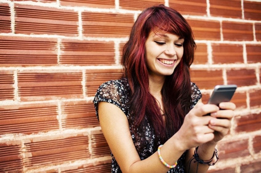 Red haired girl smiling texting