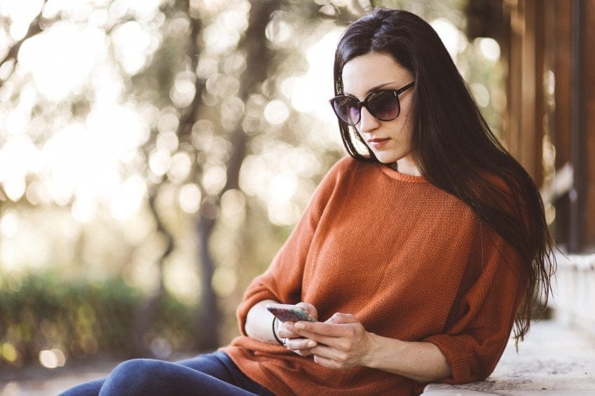 Brunette sat in park texting