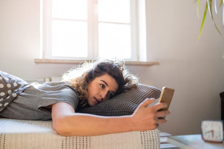 Woman texting in bed.