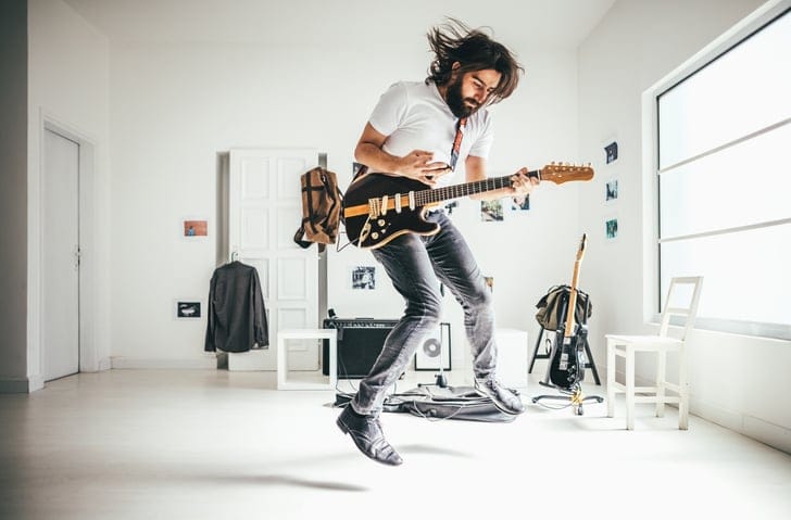 Man playing his guitar in the house.
