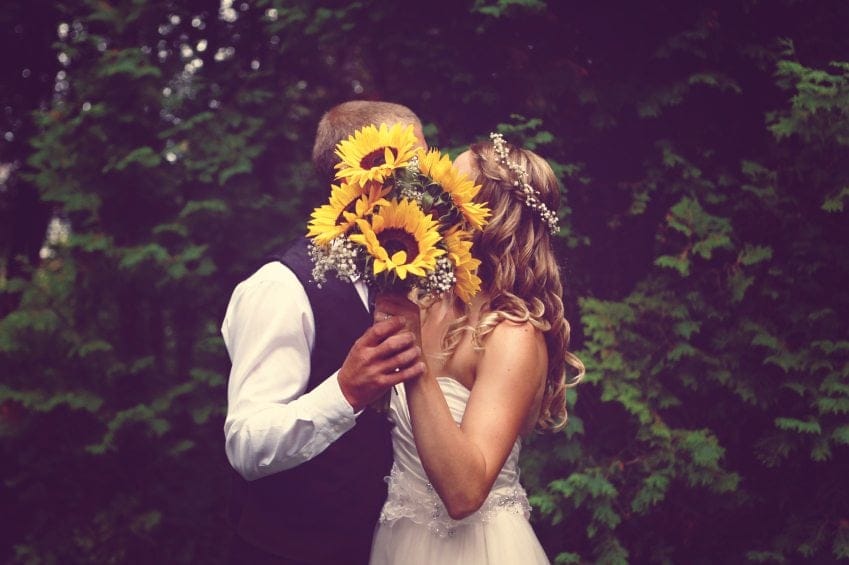 Bride and groom behind flower