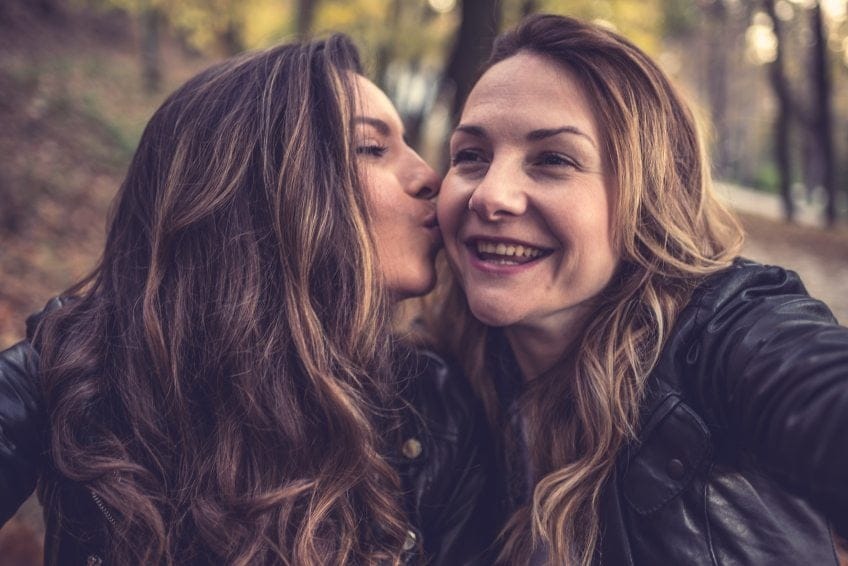 Two friends kiss on cheek