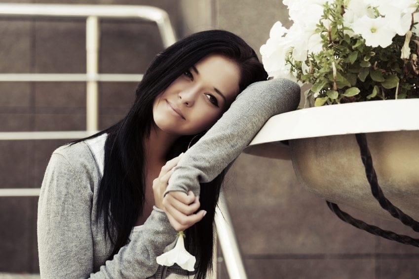Happy young fashion woman with a flower daydreaming