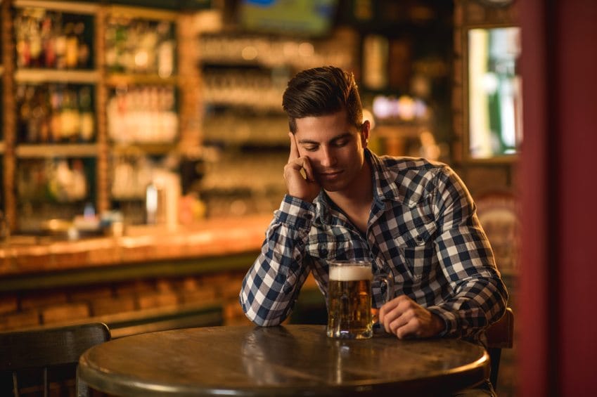 Young pensive man sitting alone in a bar.