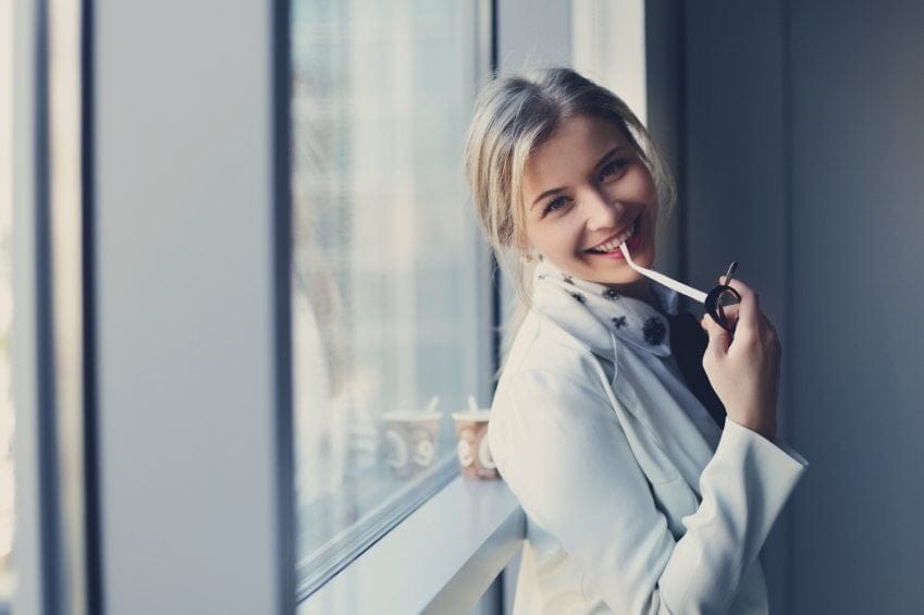 Young blonde smiling holding glasses