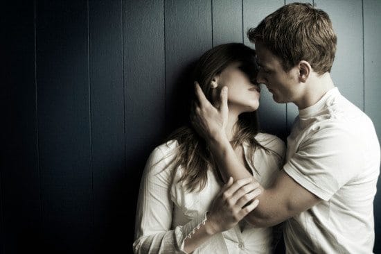 man kissing woman in dark room