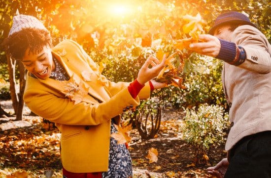 couple play fighting in autumn leaves