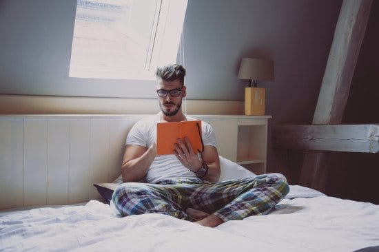 man reading book in bed