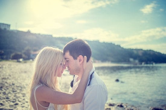 newlywed couple kissing on beach