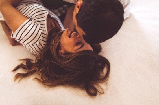 laughing couple kissing in bed