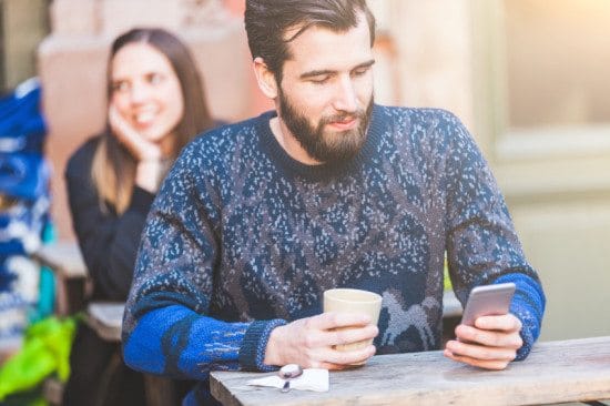 man texting with coffee