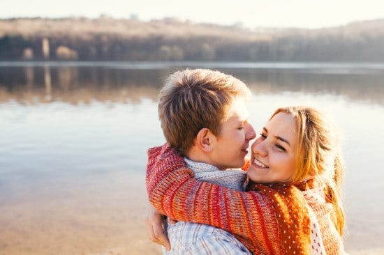 couple sharing hug by sunny lake