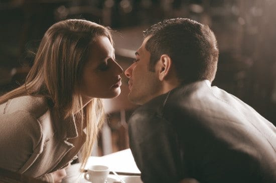 couple kissing over cafe table