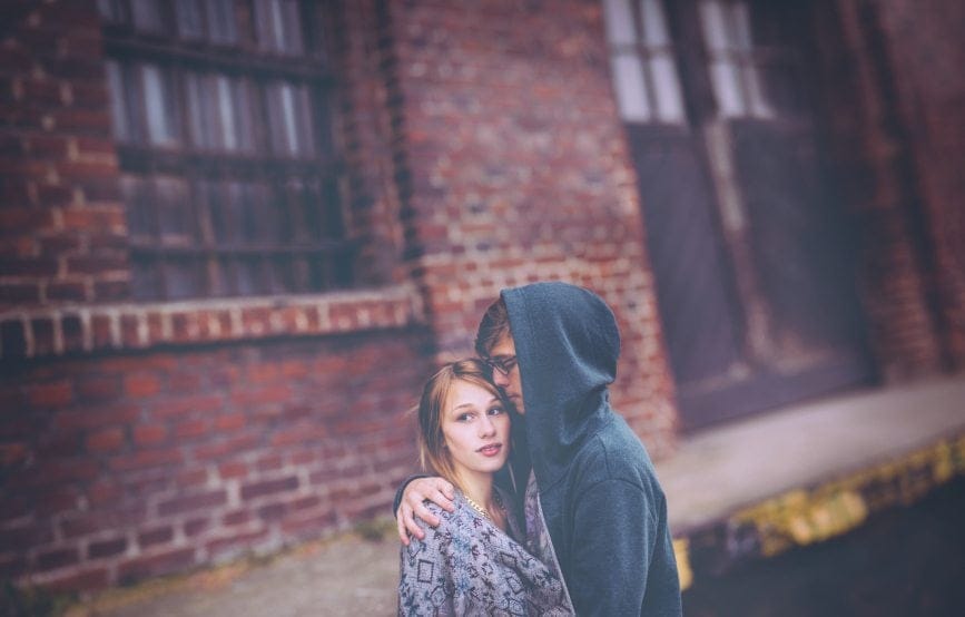 serious couple hugging on street