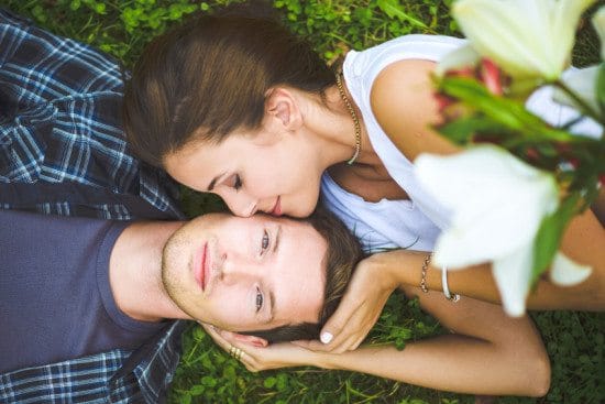 woman kissing boyfriend's face in grass