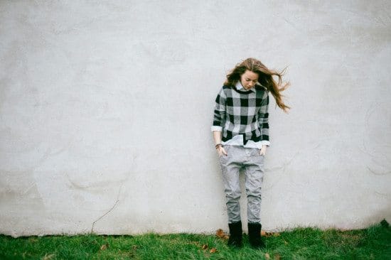 sad teen in plaid shirt leaning on wall