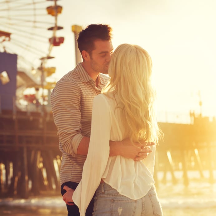 couple kissing at amusement park at sunset