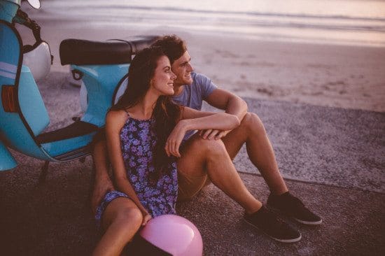 couple leaning on scooter on beach