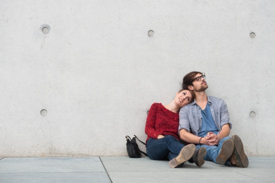 couple sitting against wall outdoors