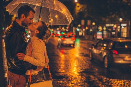 couple sharing kiss under umbrella