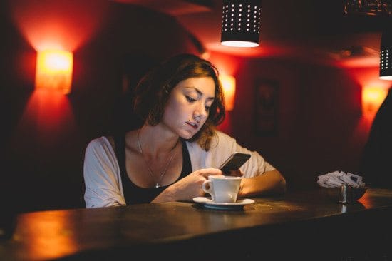 serious woman texting in dim cafe