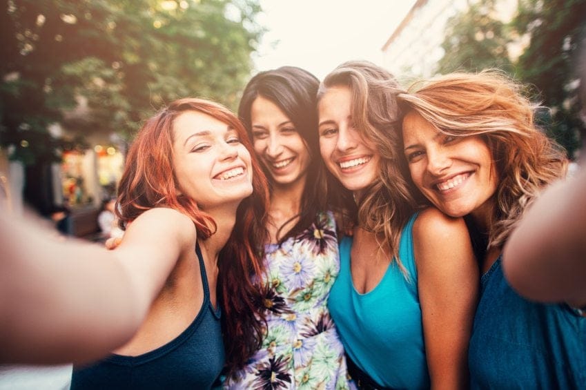 four smiling friends taking selfie