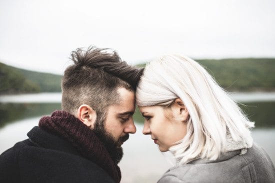 couple near lakeside touching foreheads