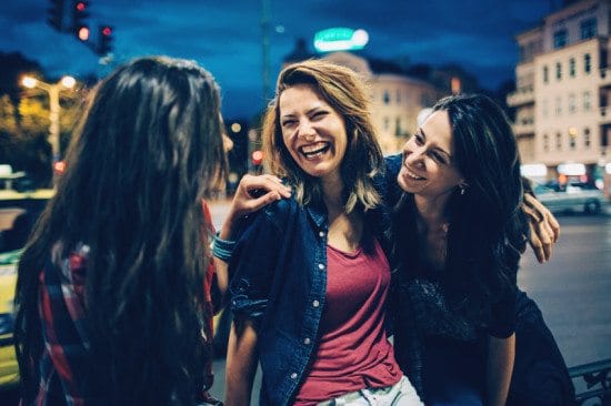 3 female friends laughing at night