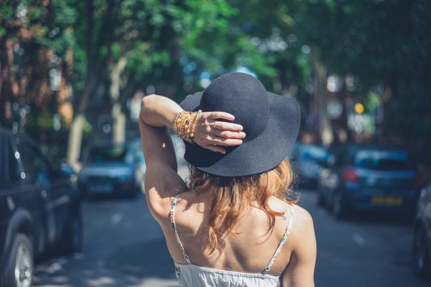 woman in hat walking city streets