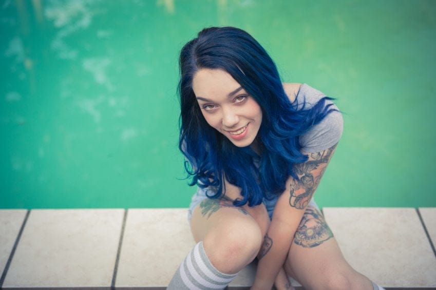 tattooed woman smiling by pool