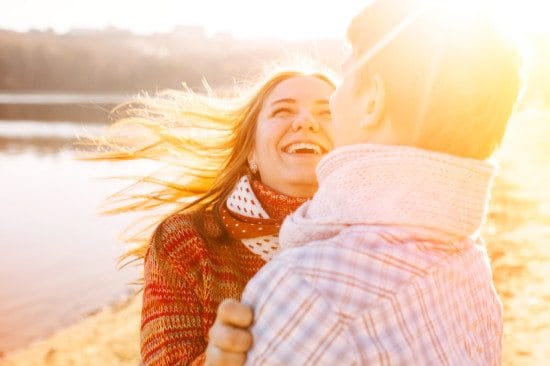 laughing couple by winter lakeside