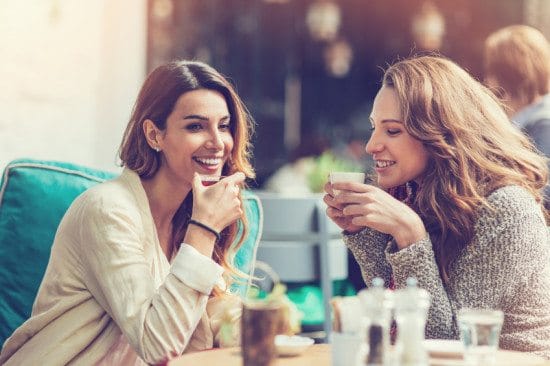 Female friends gossiping at cafe.
