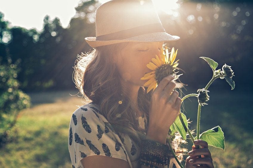 woman smelling sunflower outdoors
