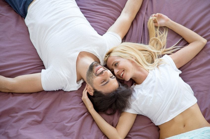 happy couple in white shirts in bed